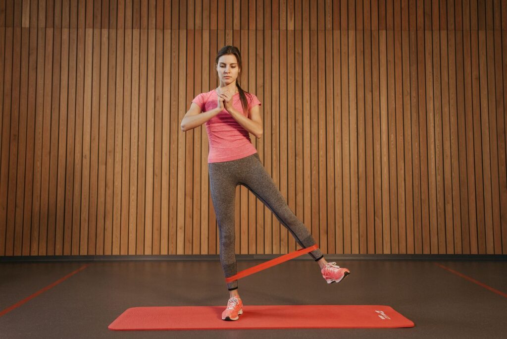 pexels-photo-6339643-6339643 A woman performs leg exercises with a resistance band at a gym, promoting fitness and healthy living.